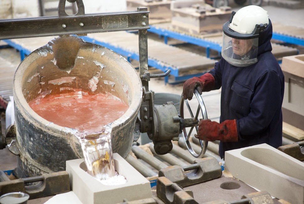 Pouring molten metal into a small sand casting mould